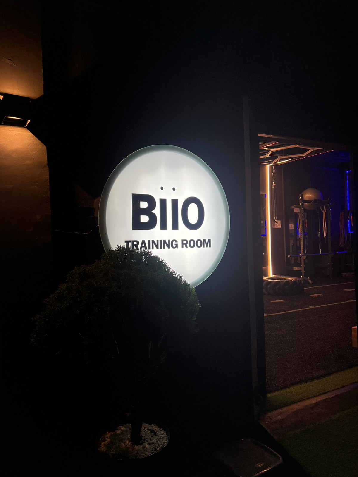 Letrero iluminado de BIIO Training Room en la entrada, de noche